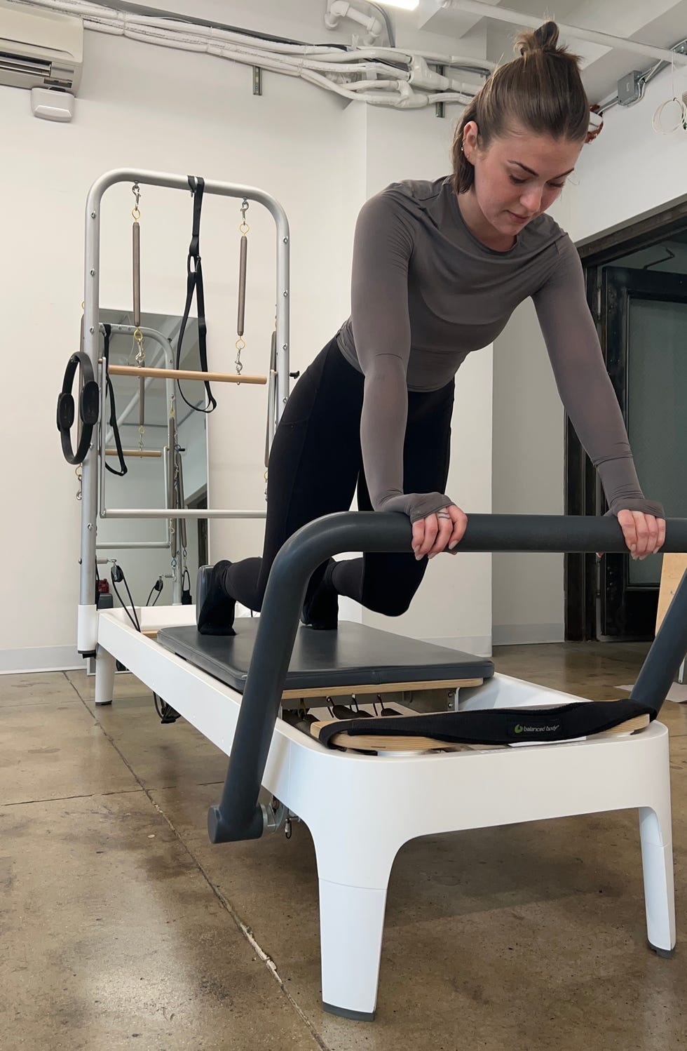 fitness editor talene doing a pilates sequence with her hands on the allegro 2 pilates reformer leg machine