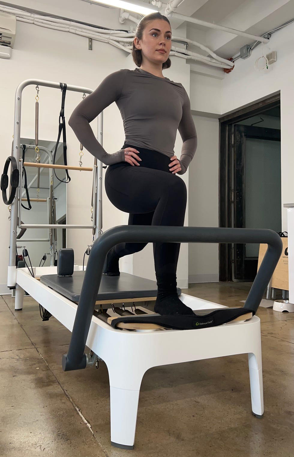 women's health editor and writer talene appleton tests the allegro 2 pilates reformer machine in her apartment for a home pilates workout